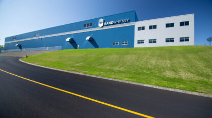 A blue building with a grassy field in the foreground.