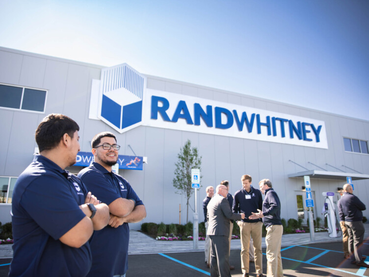 A group of men standing in front of a rand whitney building.
