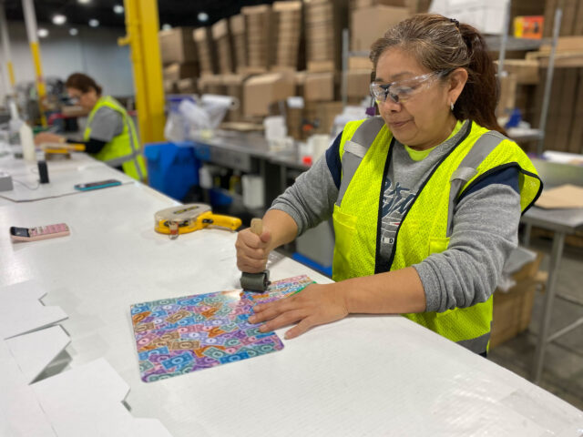 A woman in a vest working on a piece of paper.