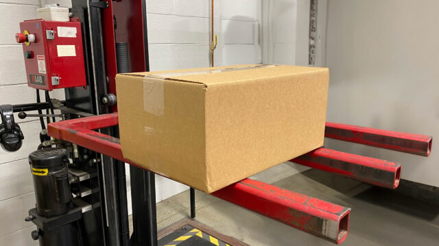 A box sitting on a forklift in a warehouse.
