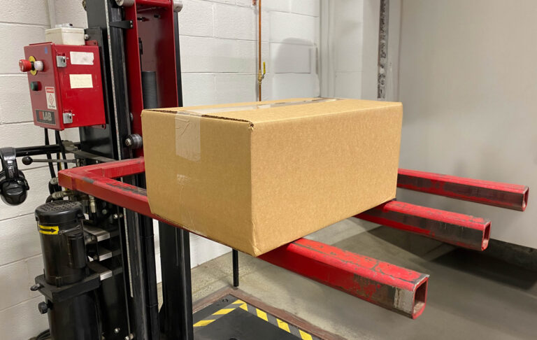 A box sitting on a forklift in a warehouse.