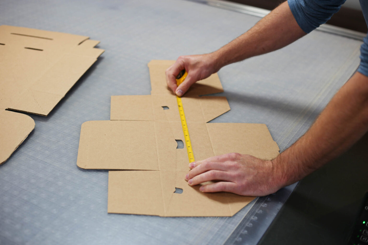 A man measuring cardboard boxes with a measuring tape.