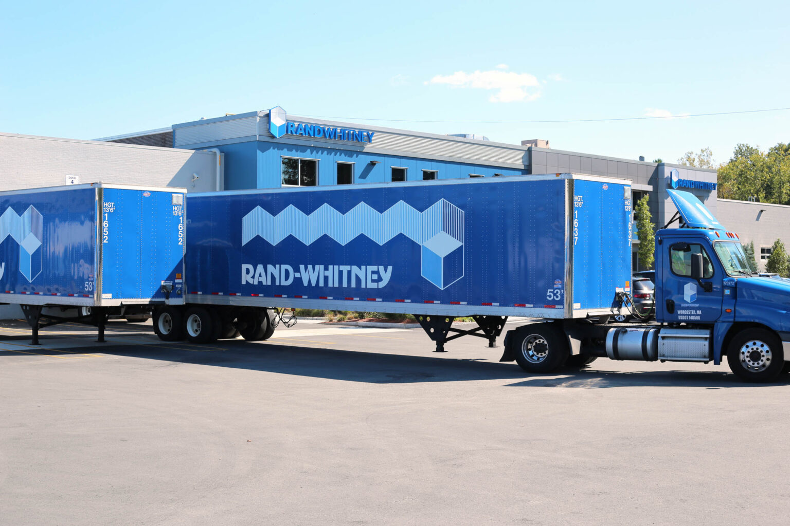 A blue semi truck parked in front of a building.