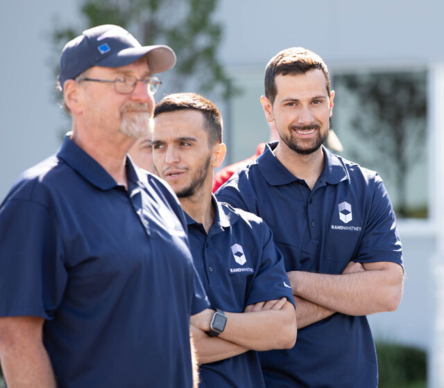 A group of men in blue shirts standing in front of a building.