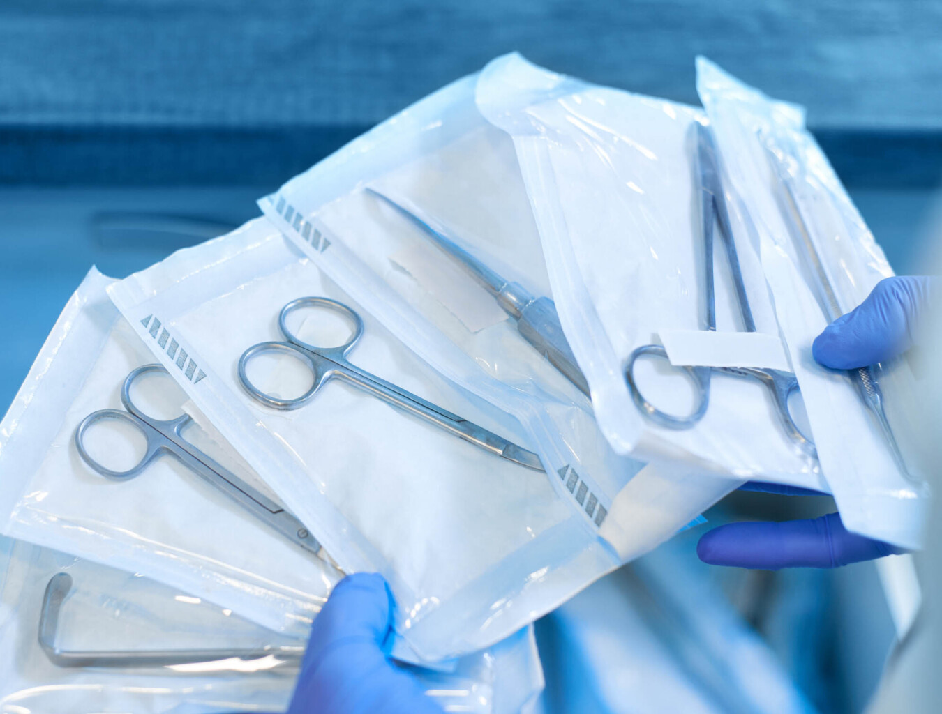 A person is holding a pair of surgical tools in packaging.