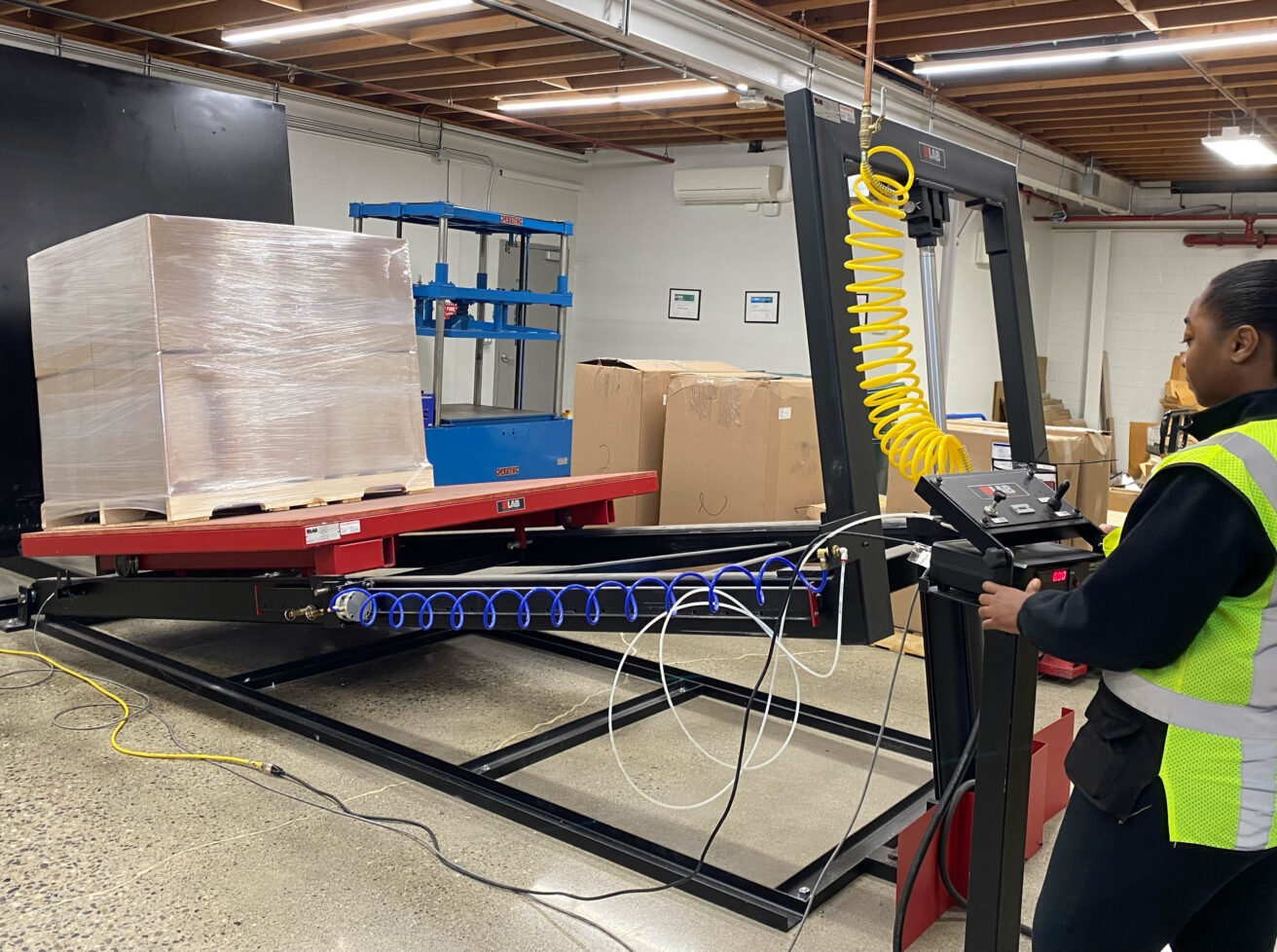 A worker is working on a pallet jack in a warehouse.