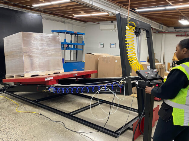 A worker is working on a pallet jack in a warehouse.