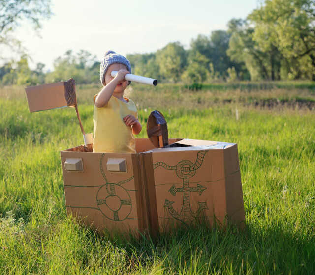 A girl dressed up as a pirate in a cardboard box.