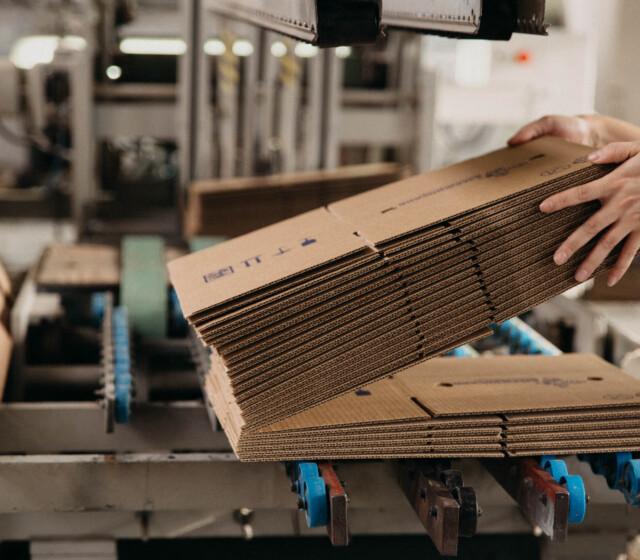 A person stacking cardboard boxes in a factory.