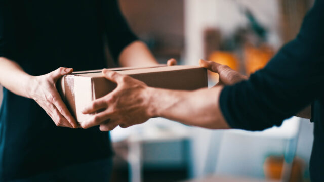 A woman handing a box to a man.