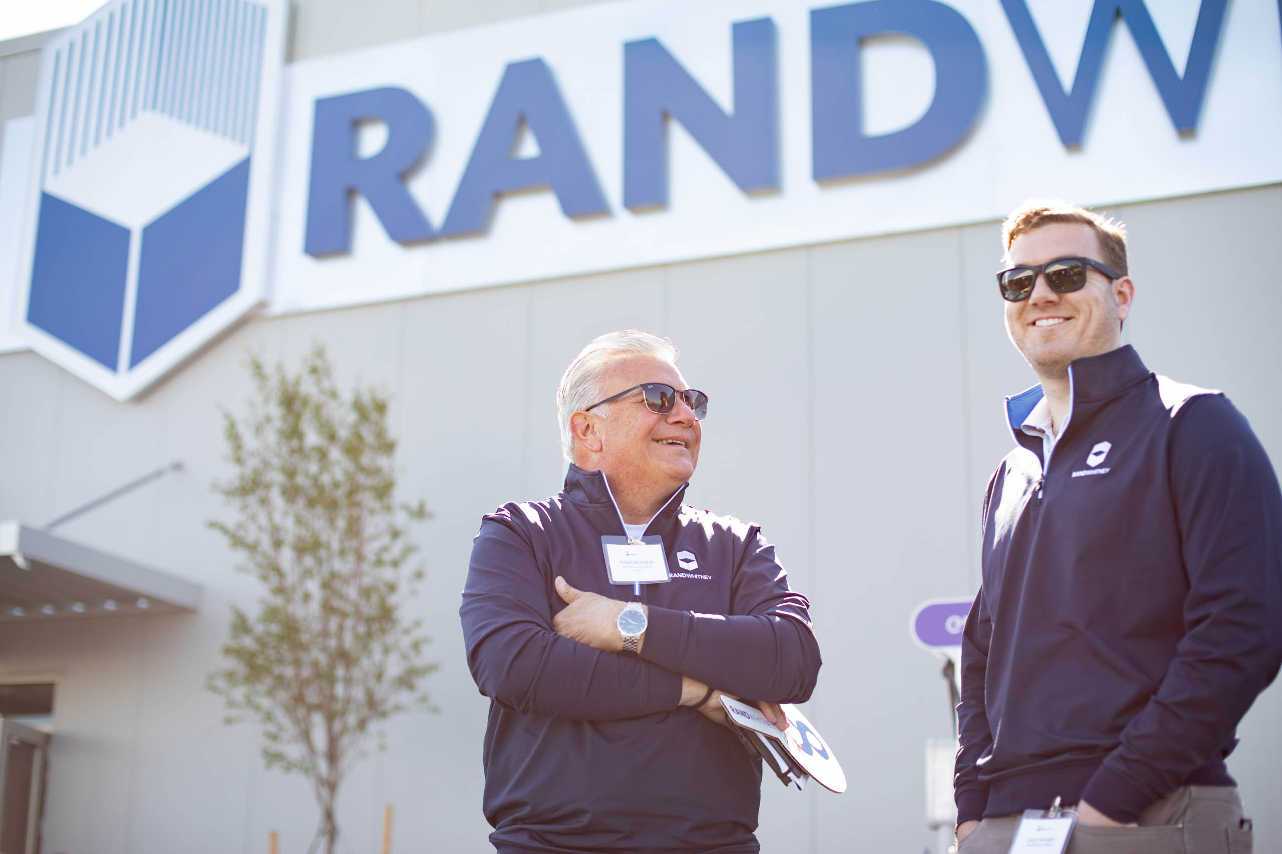 Two employees talking outside a Rand Whitney building.